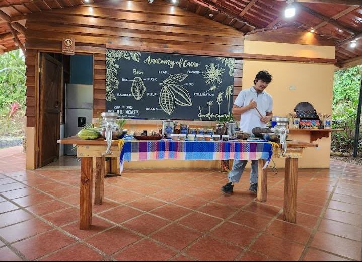 Guía explicando el proceso del cacao junto al mural 'Anatomía del Cacao'