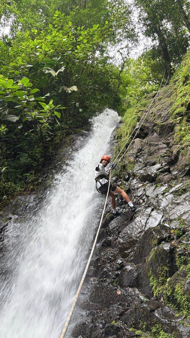 Persona haciendo rappel por una catarata en la selva